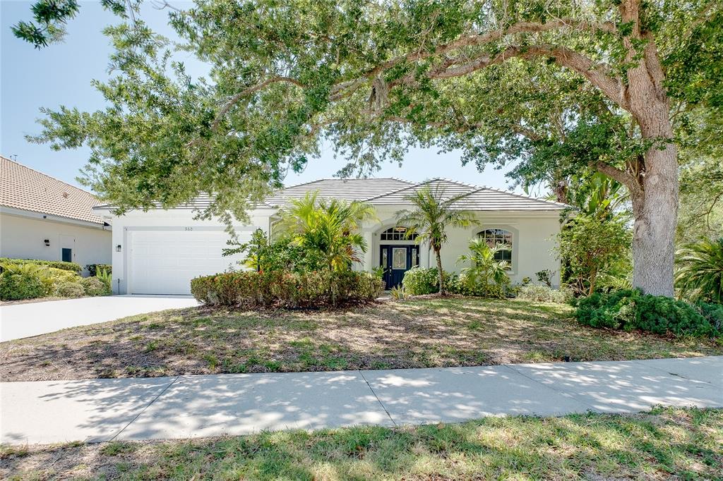 A single-story house with a white exterior, a two-car garage, and mature trees — 360 CEDARBROOK COURT, VENICE, FL