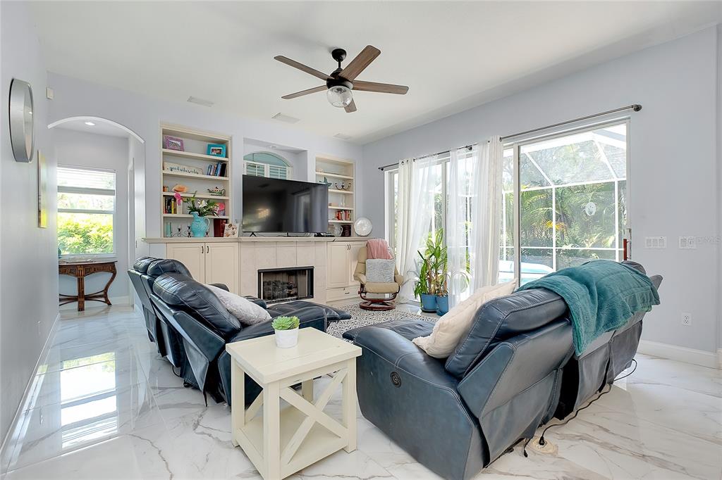 A living room features blue leather recliners, a fireplace with built-in shelves, and marble flooring — 360 CEDARBROOK COURT, VENICE, FL