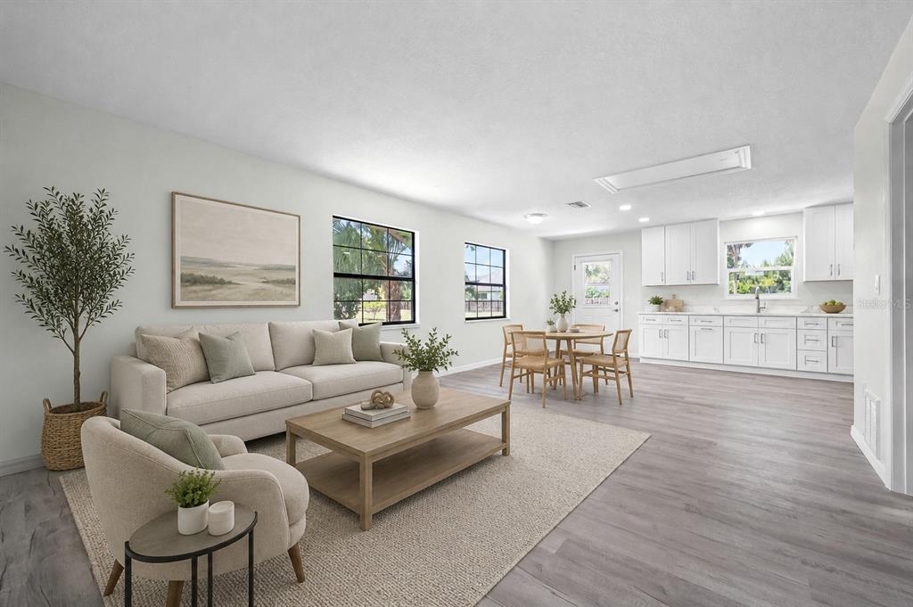 This is a digitally staged open-concept living and dining area with white cabinetry and wood flooring — 2331 MISSION VALLEY BOULEVARD, NOKOMIS, FL