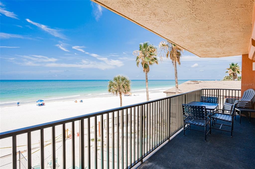 A balcony with outdoor furniture overlooks a sandy beach and the ocean — 17334 GULF BOULEVARD UNIT 203, NORTH REDINGTON BEACH, FL