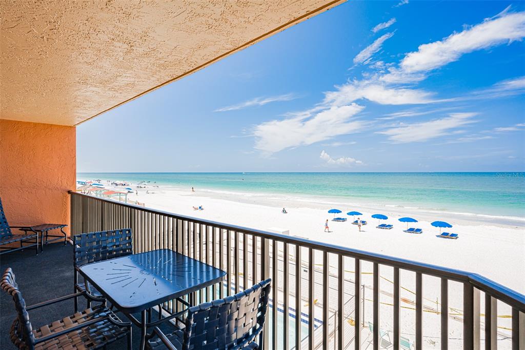 A balcony with outdoor furniture overlooks a sandy beach and the ocean under a blue sky — 17334 GULF BOULEVARD UNIT 203, NORTH REDINGTON BEACH, FL