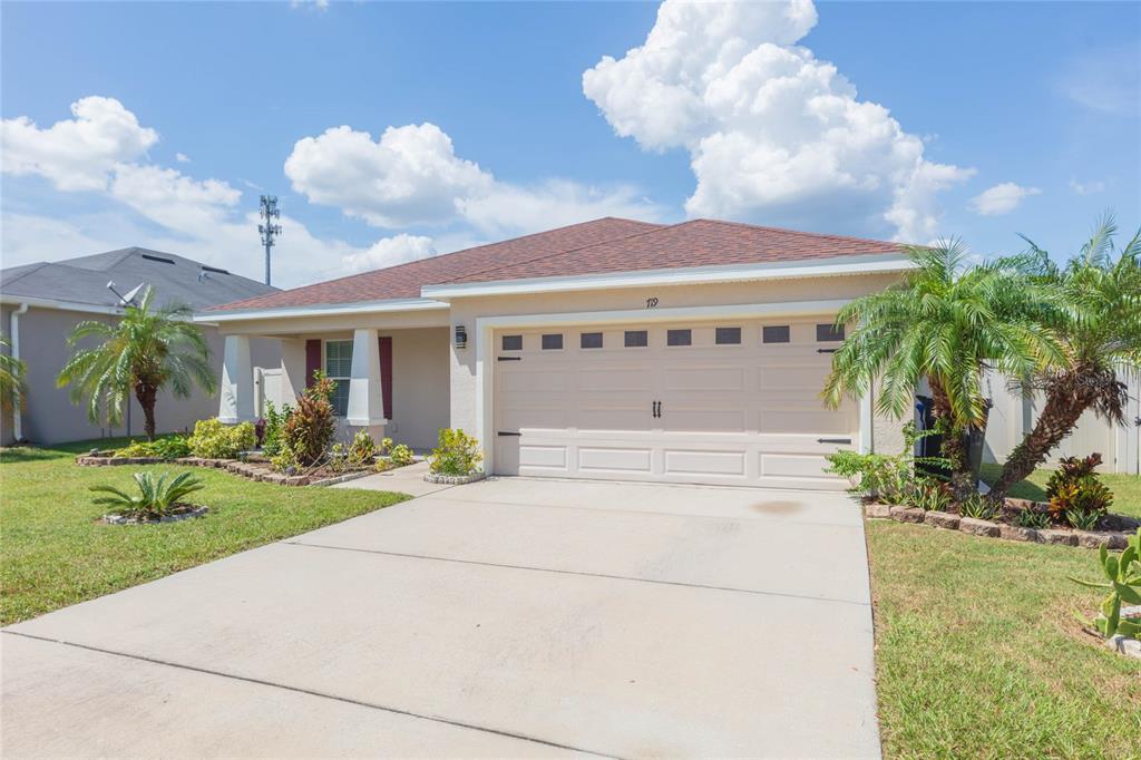 A single-story house with a beige stucco exterior, a two-car garage, and a palm tree — 719 VINEYARD RESERVE COURT, SEFFNER, FL