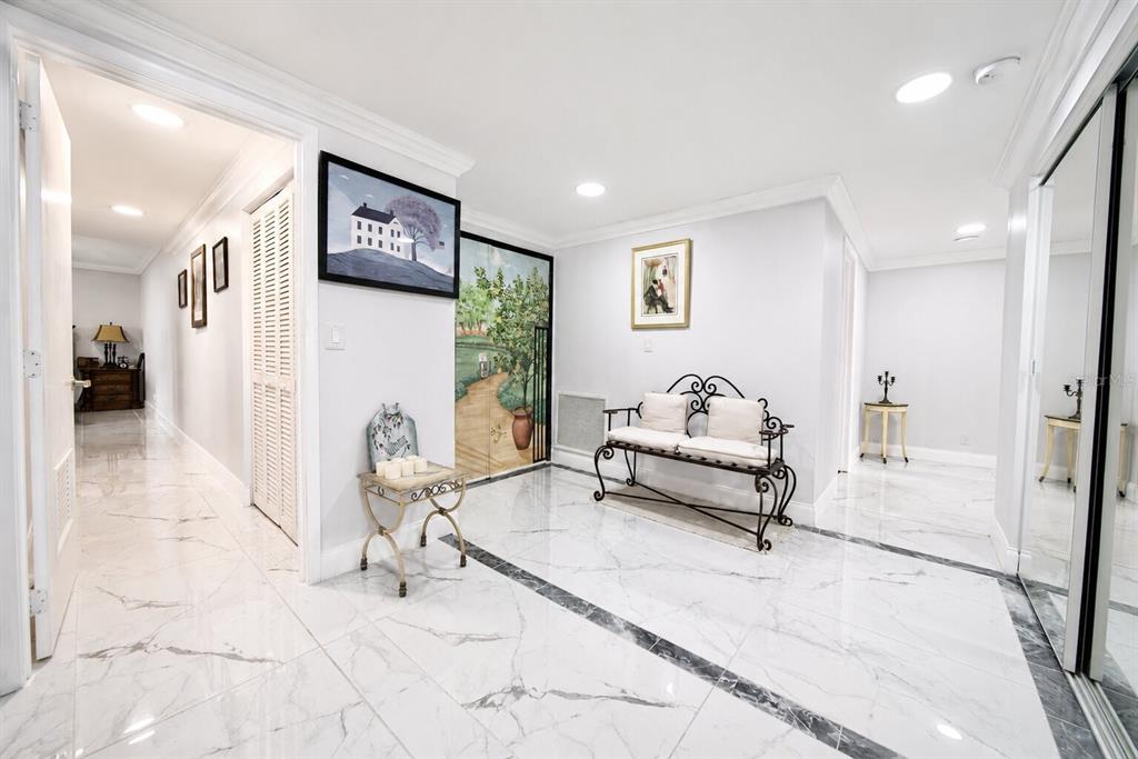 A bright foyer features white marble floors, a decorative metal bench, and a mural-covered door — 1501 GULF BOULEVARD UNIT 305, CLEARWATER BEACH, FL