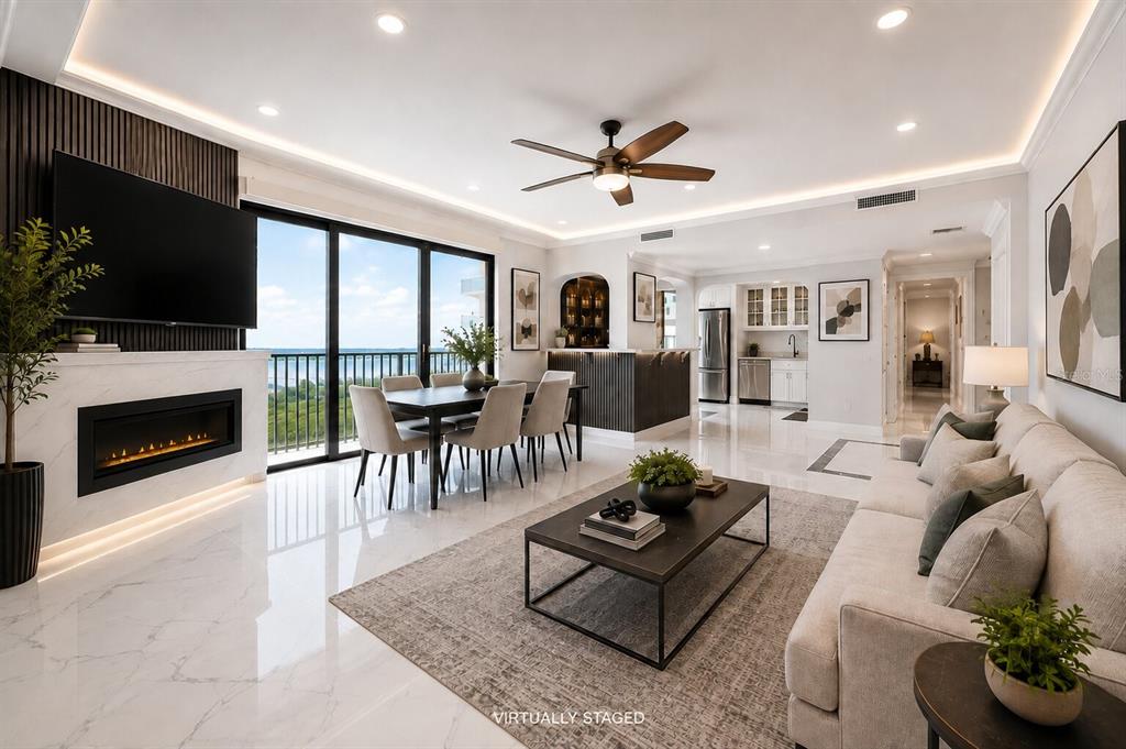 A modern living room with a fireplace, dining area, and kitchen features white marble floors — 1501 GULF BOULEVARD UNIT 305, CLEARWATER BEACH, FL