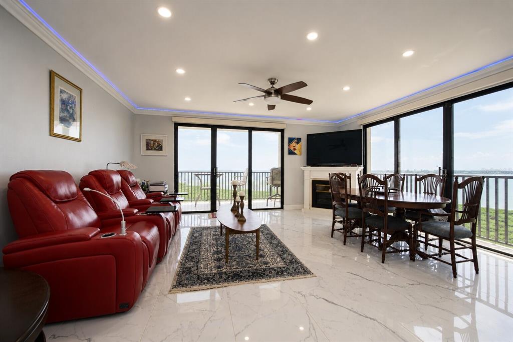 A living and dining room with red leather recliners, marble floors, and a balcony view — 1501 GULF BOULEVARD UNIT 305, CLEARWATER BEACH, FL