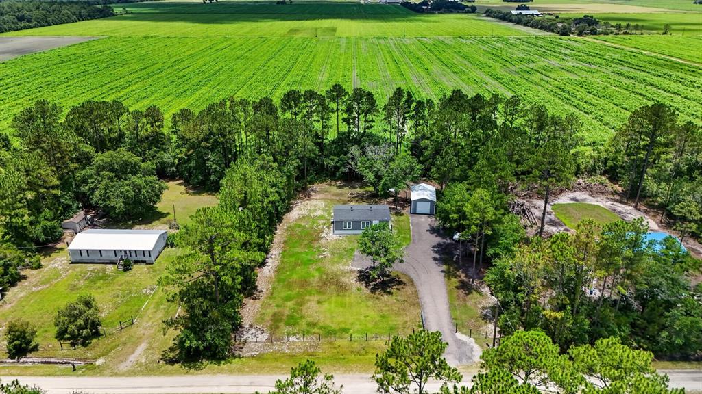 A gray metal storage shed with a white roll-up garage door sits on a gravel lot — 4825 PECAN AVENUE, BUNNELL, FL