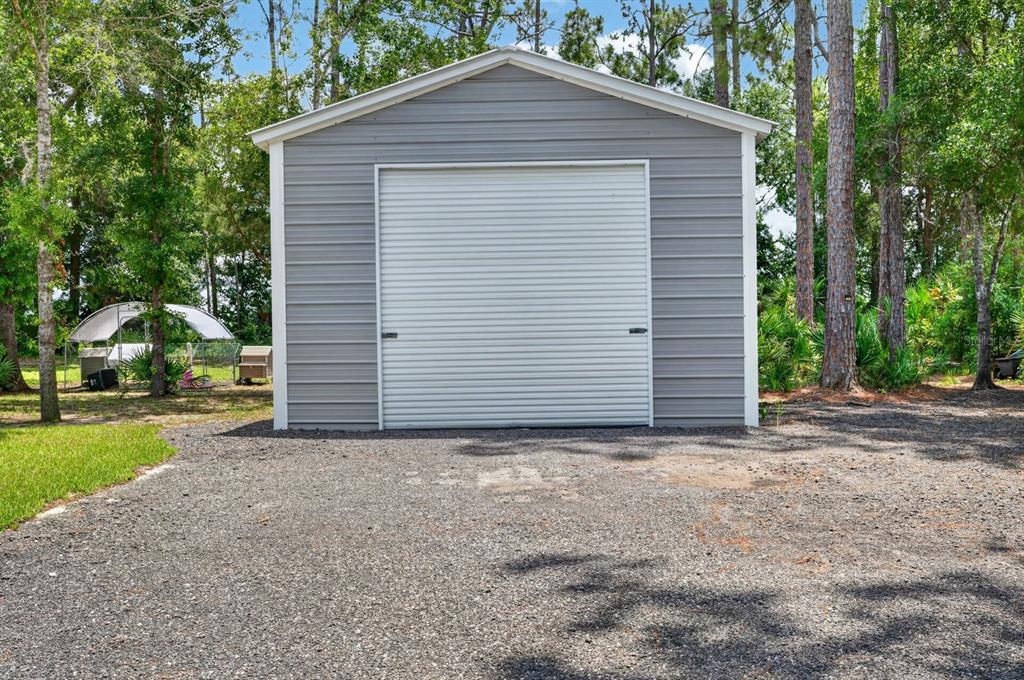 A metal storage shed contains a boat on a trailer and a yellow riding lawnmower — 4825 PECAN AVENUE, BUNNELL, FL
