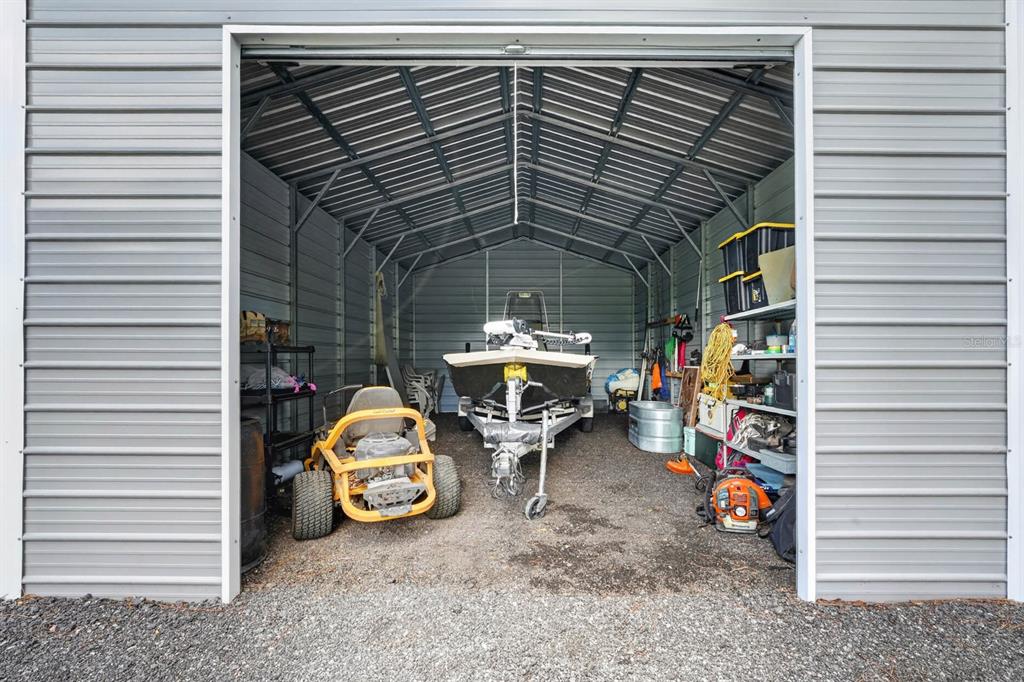 A gravel driveway leads through a gated entrance toward a house and detached garage — 4825 PECAN AVENUE, BUNNELL, FL