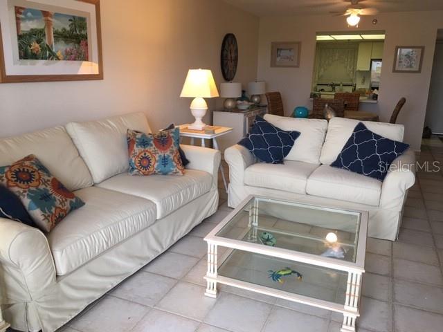 A living room features two white sofas, a glass coffee table, and tiled flooring — 1001 BENJAMIN FRANKLIN DRIVE UNIT 505, SARASOTA, FL