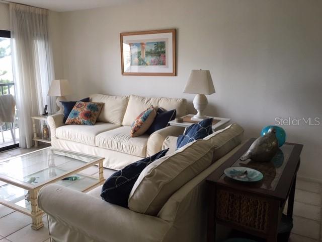 A living room features a beige sofa, a glass coffee table, and a side table — 1001 BENJAMIN FRANKLIN DRIVE UNIT 505, SARASOTA, FL