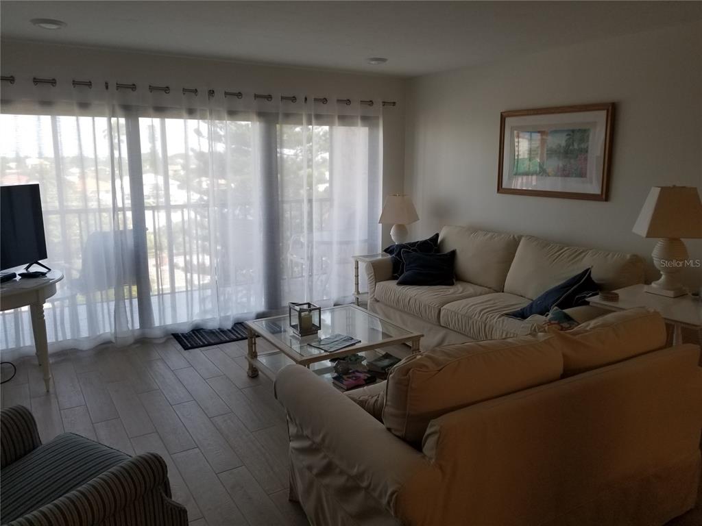 A living room features two beige sofas, a glass coffee table, and large sliding glass doors — 1001 BENJAMIN FRANKLIN DRIVE UNIT 505, SARASOTA, FL