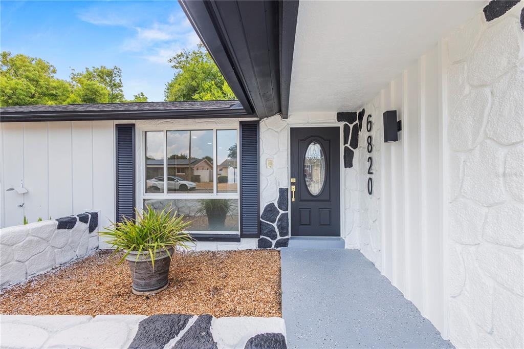 A front entryway features a dark door, white stone siding, and a gray concrete porch — 6820 EL CAMINO PALOMA STREET, PORT RICHEY, FL