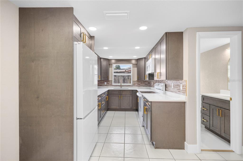 A living room with white tile floors, recessed lighting, and a wood-slatted accent wall feature — 6820 EL CAMINO PALOMA STREET, PORT RICHEY, FL