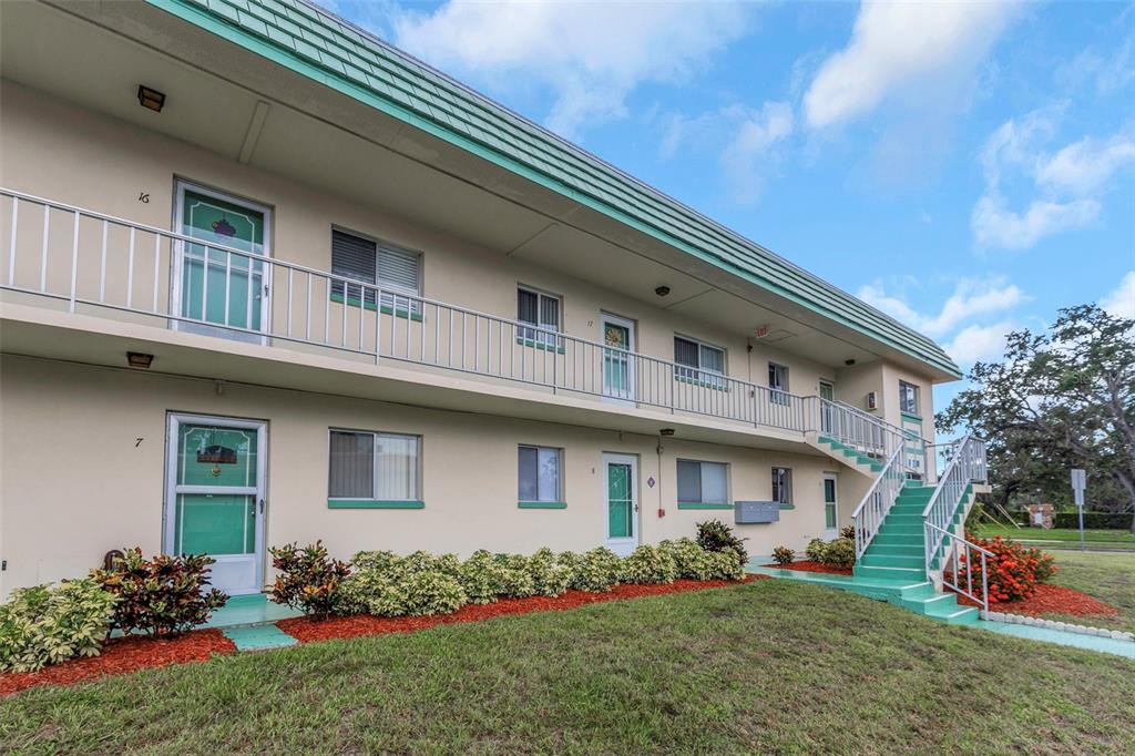 A two-story apartment building with a green roof, exterior stairwell, and numbered unit doors — 2001 GREENBRIAR BOULEVARD UNIT 17, CLEARWATER, FL