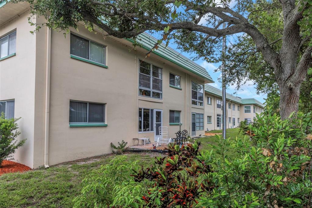 The exterior of a multi-story apartment building features beige stucco walls and green trim — 2001 GREENBRIAR BOULEVARD UNIT 17, CLEARWATER, FL