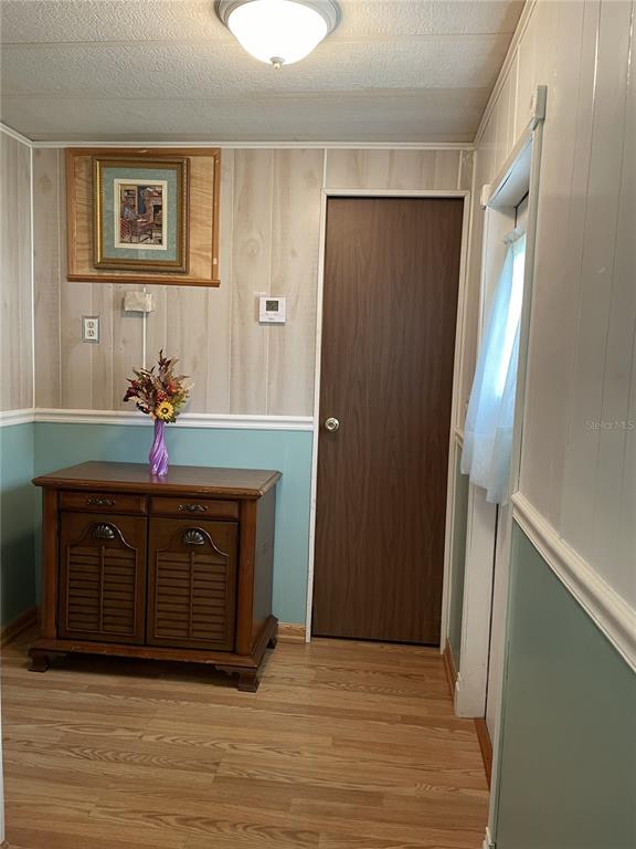 A room with wood-paneled walls, a wooden cabinet, a door, and light-colored wood flooring — 1020 LAUREL COURT W, PALM BAY, FL