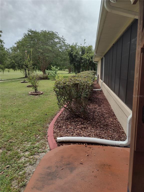 A view of a house exterior with a screened porch, landscaping, and a lawn — 592 DOWLING CIRCLE, LADY LAKE, FL