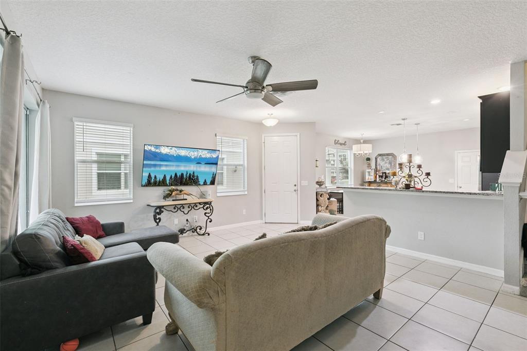 A living room features tile flooring, a ceiling fan, a sofa, and a television — 6803 TUSSILAGO WAY, ORLANDO, FL