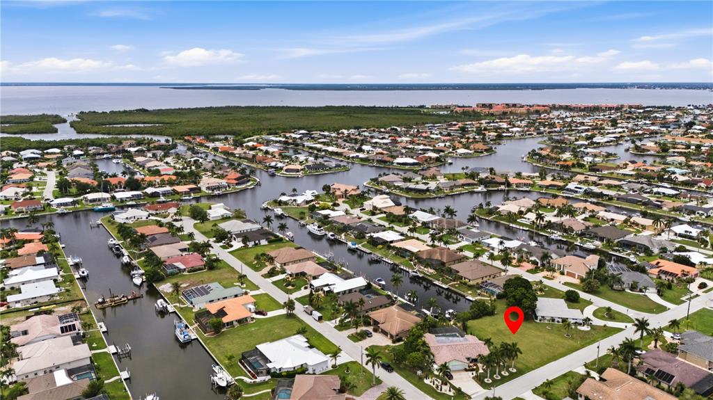 This aerial view shows a residential neighborhood with houses along canals and a vacant lot — 1121 CORONADO DRIVE, PUNTA GORDA, FL