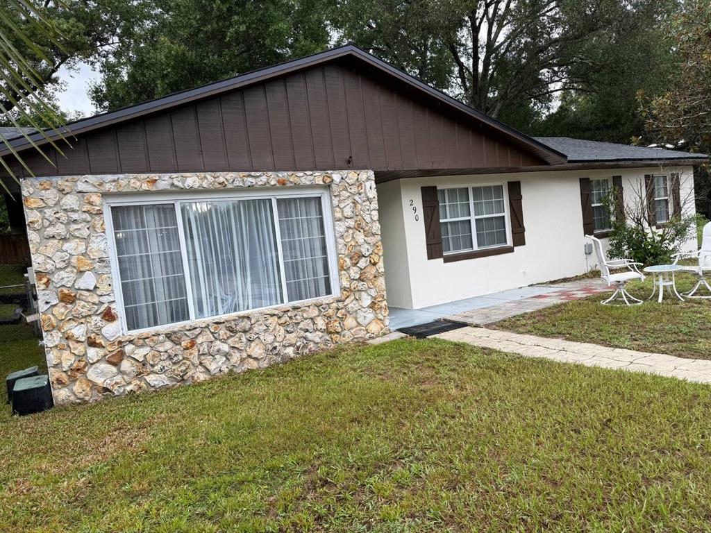 A single-story house with a stone facade, brown siding, and a white front entrance — 290 HILLSIDE DRIVE, CLERMONT, FL