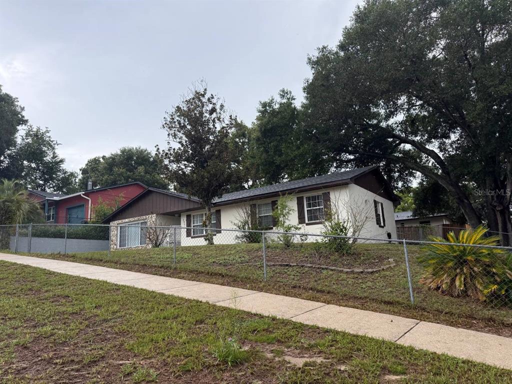 A single-story house with a white exterior and brown trim sits behind a chain-link fence — 290 HILLSIDE DRIVE, CLERMONT, FL