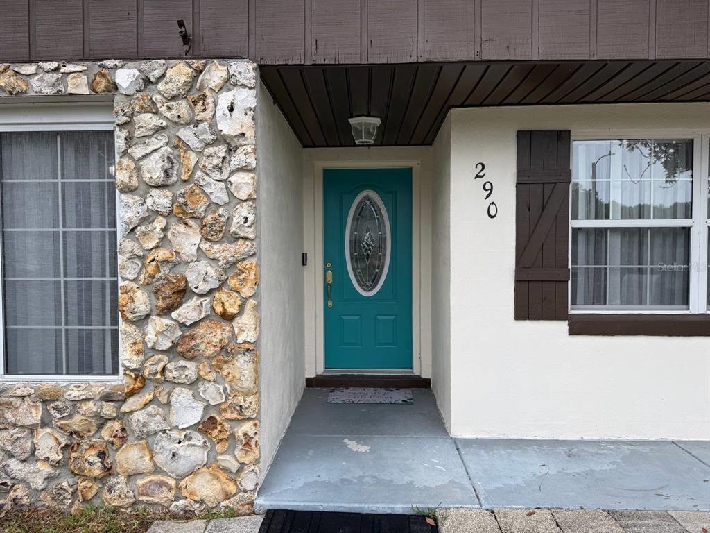 The exterior of a home features a teal front door, stone siding, and brown shutters — 290 HILLSIDE DRIVE, CLERMONT, FL