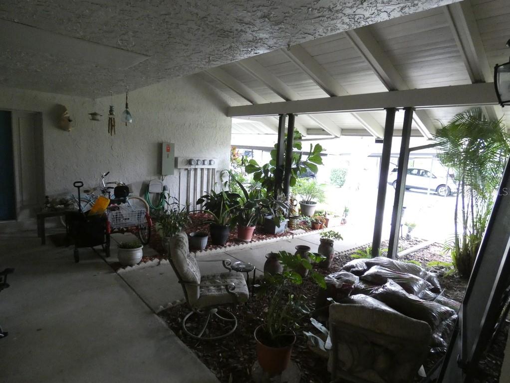 A covered patio area features a concrete floor, potted plants, and a seating area — 1024 10TH CIRCLE SE, LARGO, FL