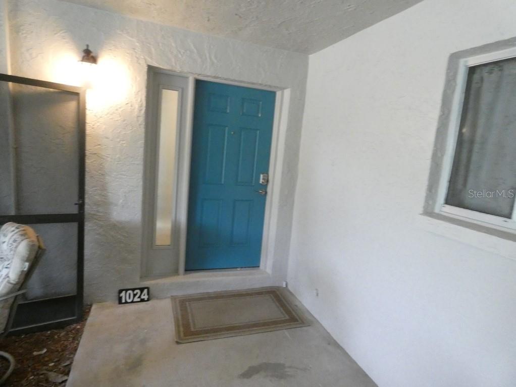 A blue front door with a side window and a house number on a porch — 1024 10TH CIRCLE SE, LARGO, FL