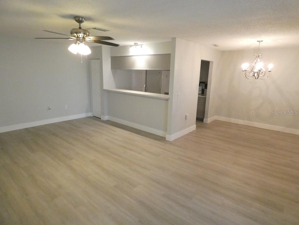 An open-concept living and dining area features light wood-look flooring and a kitchen pass-through window — 1024 10TH CIRCLE SE, LARGO, FL