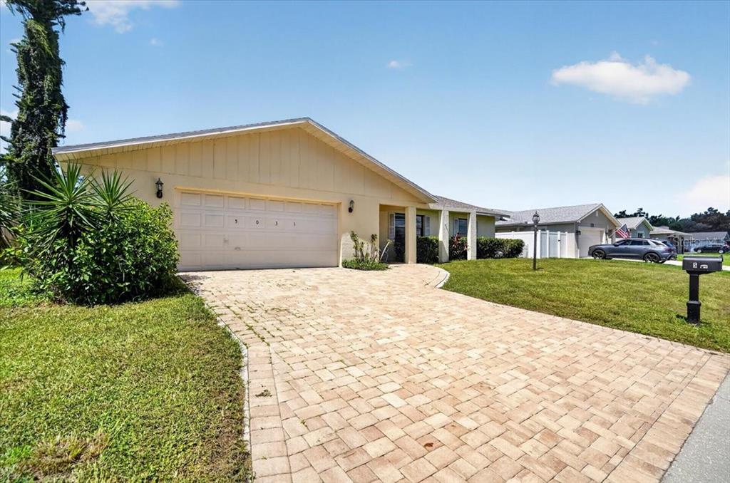 A single-story house with a beige exterior, a two-car garage, and a paved driveway — 5031 BRANDEIS CIRCLE S, SARASOTA, FL