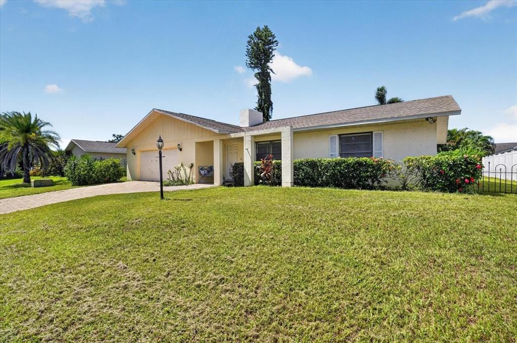 A single-story house with a beige exterior, a two-car garage, and a large front lawn — 5031 BRANDEIS CIRCLE S, SARASOTA, FL