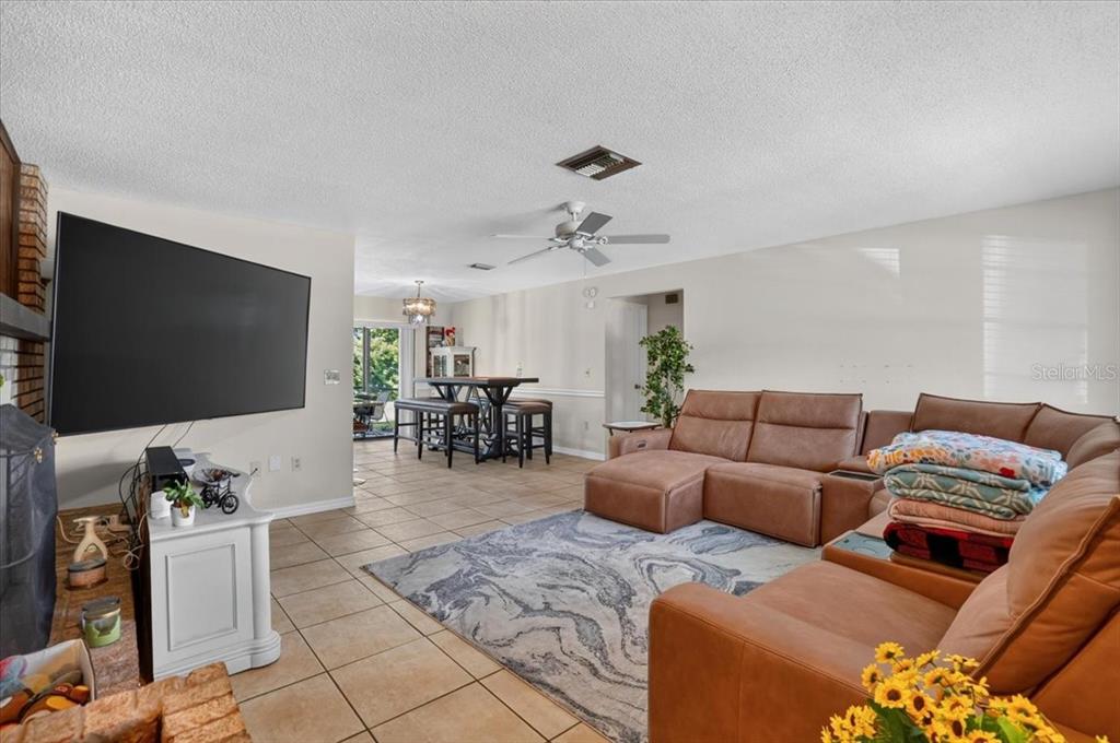 A living room features tile floors, a large sectional sofa, and a wall-mounted television — 5031 BRANDEIS CIRCLE S, SARASOTA, FL