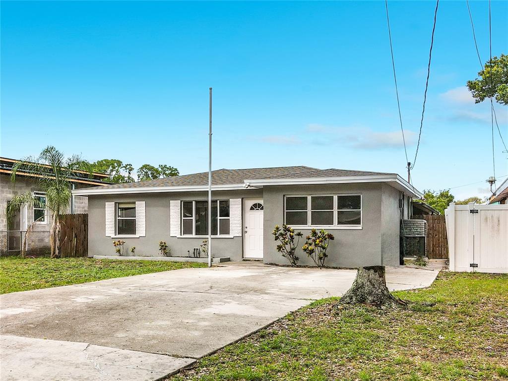 A single-story gray house with a concrete driveway and a white front door — 381 69TH STREET N, CLEARWATER, FL