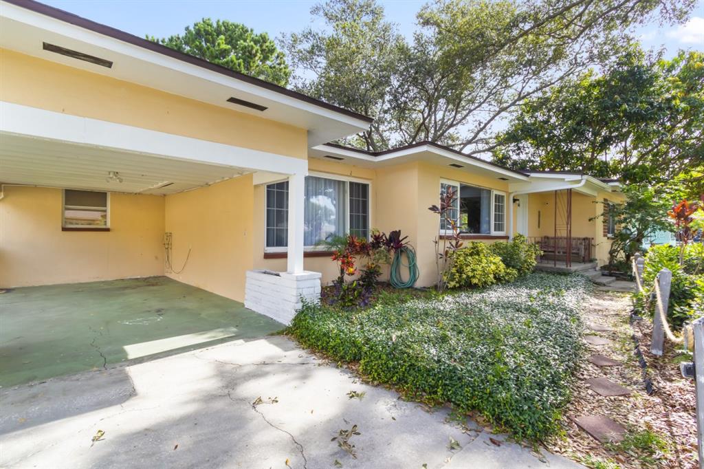A yellow single-story house with a carport, a front walkway, and mature landscaping — 1512 LIME STREET, CLEARWATER, FL