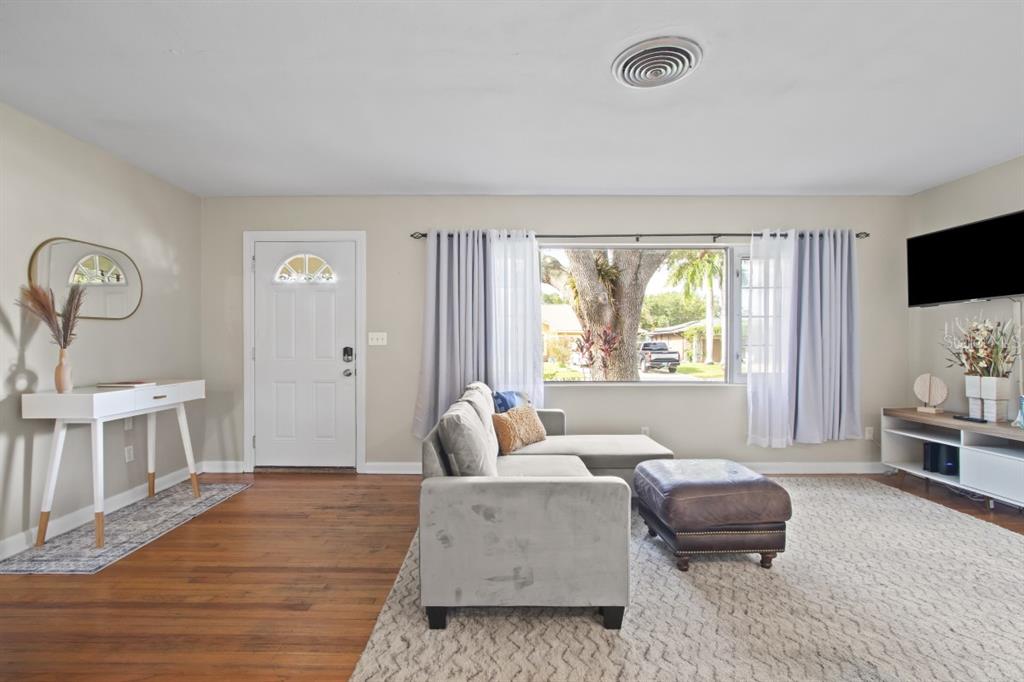 A living room features a gray sectional sofa, a white console table, and a large window — 1512 LIME STREET, CLEARWATER, FL