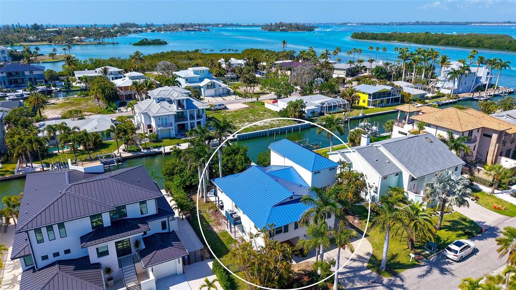 An aerial view shows a house with a blue metal roof near a canal — 771 MARBURY LANE, LONGBOAT KEY, FL