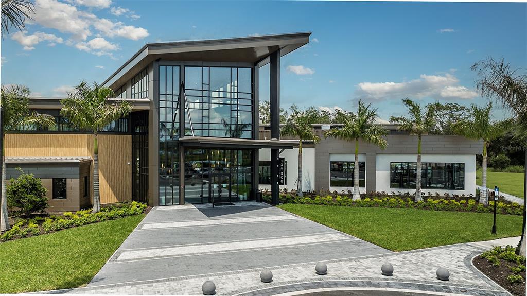 A landscaped garden with palm trees sits in front of a pool deck with lounge chairs — 7829 CENTAURUS WAY, SARASOTA, FL