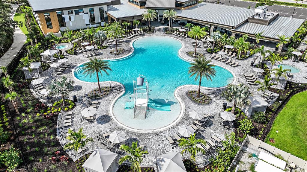 A resort-style swimming pool is surrounded by lounge chairs, palm trees, and a paved deck — 7829 CENTAURUS WAY, SARASOTA, FL