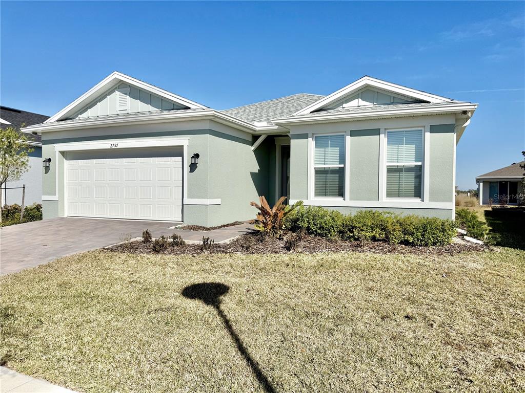 A single-story house with a light green exterior, a two-car garage, and a paved driveway — 2757 REDBLUSH TERRACE, ST CLOUD, FL