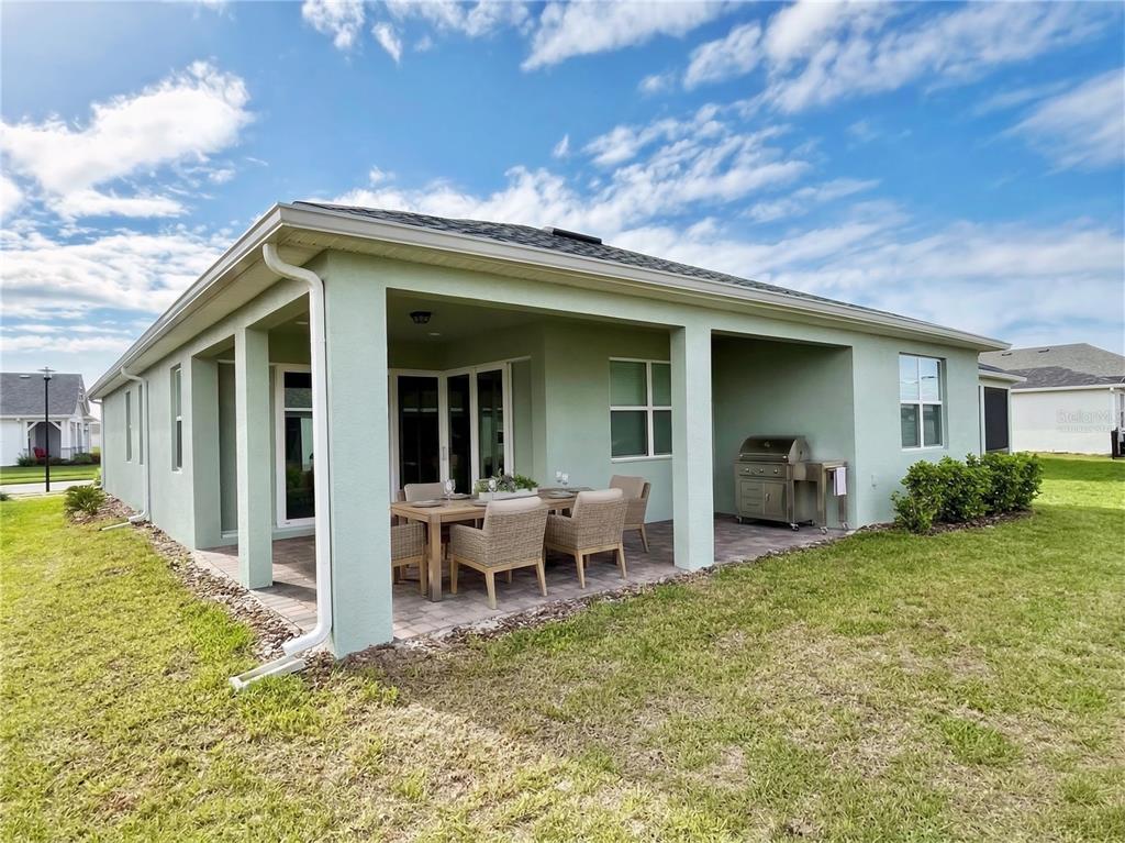 A light green house with a covered patio, outdoor dining set, and stainless steel grill — 2757 REDBLUSH TERRACE, ST CLOUD, FL