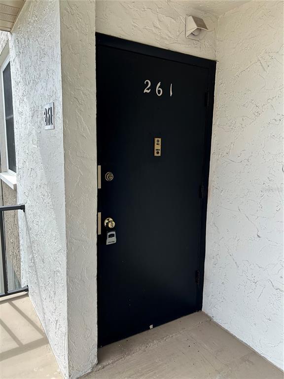 A black front door with the number 261 is set into a textured white exterior wall — 108 CLOCKTOWER DRIVE UNIT 261, BRANDON, FL