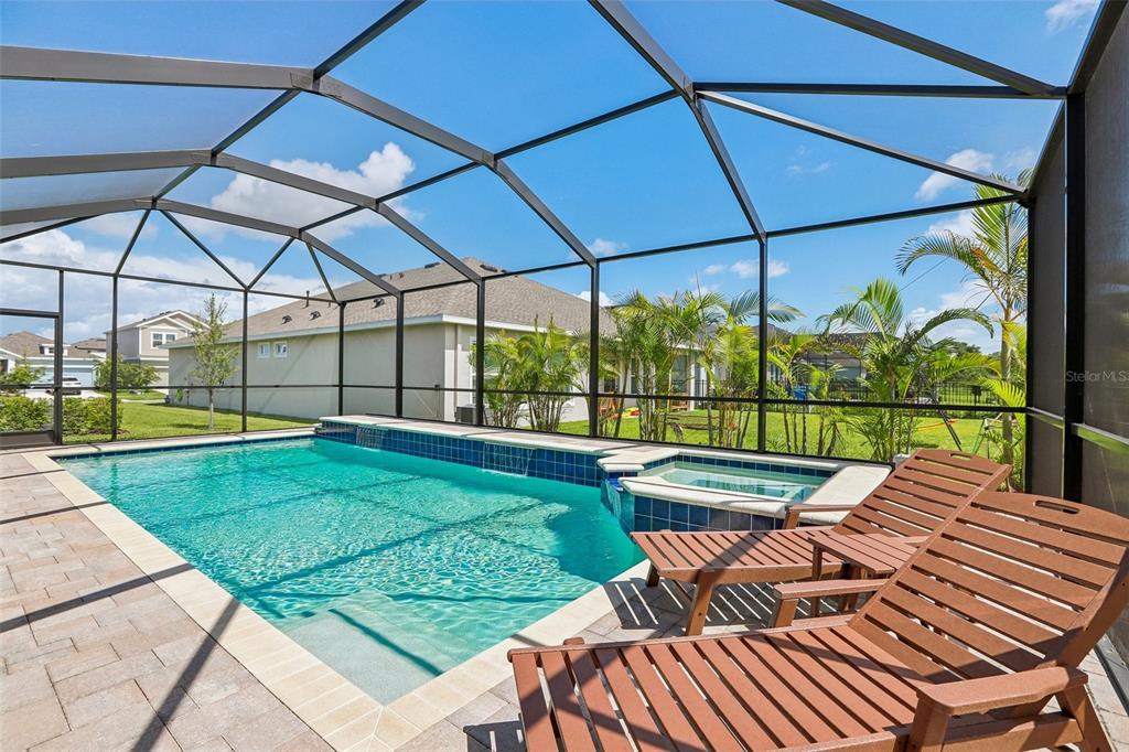 A screened-in pool and spa area with lounge chairs on a paved patio — 6092 HIDDEN BRANCH DRIVE, APOLLO BEACH, FL