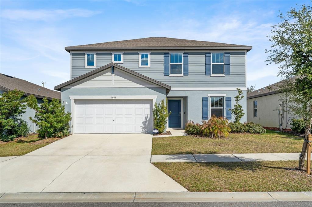 A two-story suburban house with blue siding, a white garage door, and a front lawn — 9644 SUMMERS CAY CIRCLE, THONOTOSASSA, FL