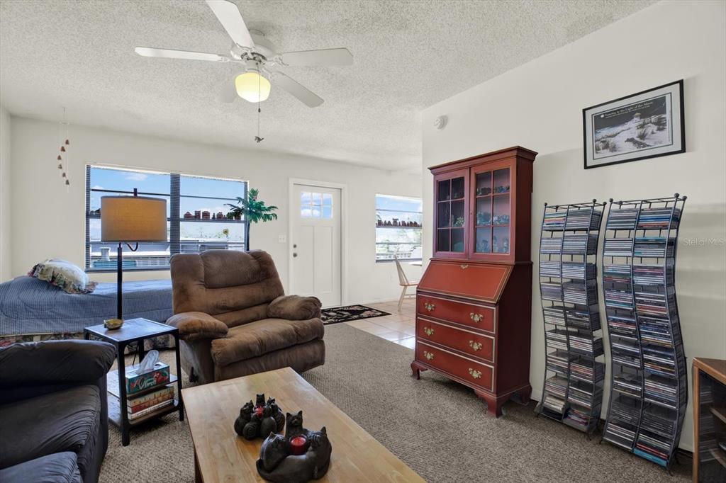 A living room features a recliner, a wooden secretary desk, and two tall media storage racks — 315 58TH STREET UNIT D, HOLMES BEACH, FL