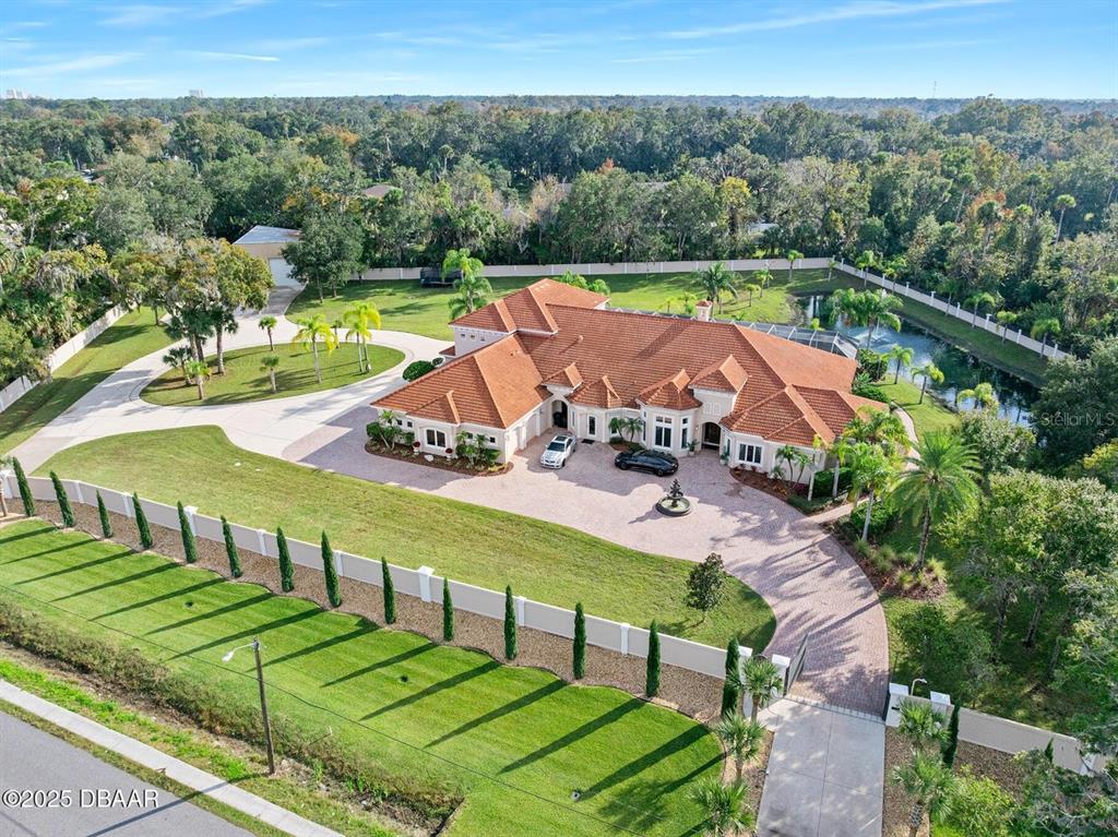 An aerial view of a large house with a tile roof, circular driveway, and pond — 602 TOMOKA AVENUE, ORMOND BEACH, FL