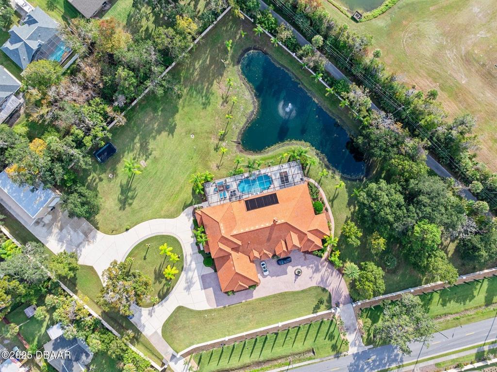 An aerial view shows a house with a tile roof, pool, and pond on a lot — 602 TOMOKA AVENUE, ORMOND BEACH, FL