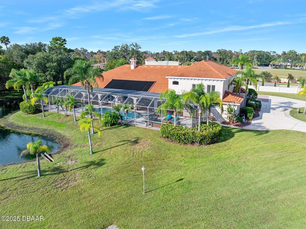 An aerial view shows a house with a tiled roof, pool enclosure, and backyard pond — 602 TOMOKA AVENUE, ORMOND BEACH, FL