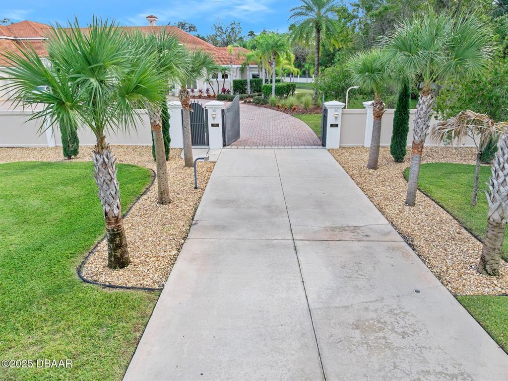 A concrete driveway leads to a gated entrance and a house with a tile roof — 602 TOMOKA AVENUE, ORMOND BEACH, FL