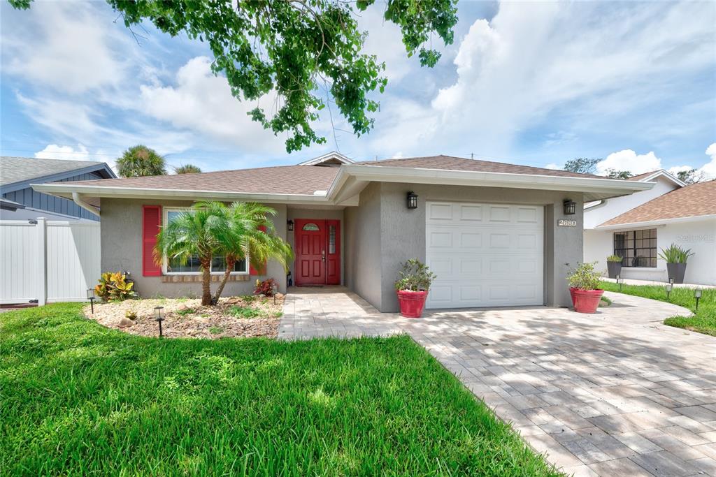 A gray house with a red front door, red shutters, and a palm tree in front — 2680 SHADYBRANCH DRIVE, ORLANDO, FL