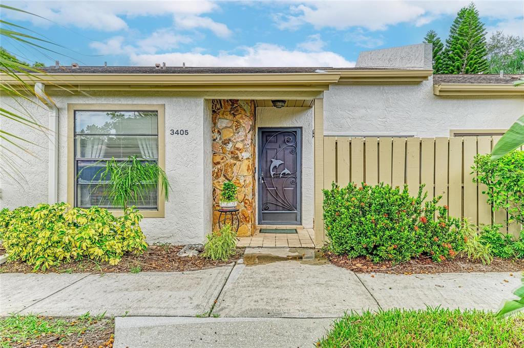 A patio with two turquoise Adirondack chairs, a metal dolphin screen door, and a fence — 3405 TALLYWOOD LANE UNIT 7130, SARASOTA, FL
